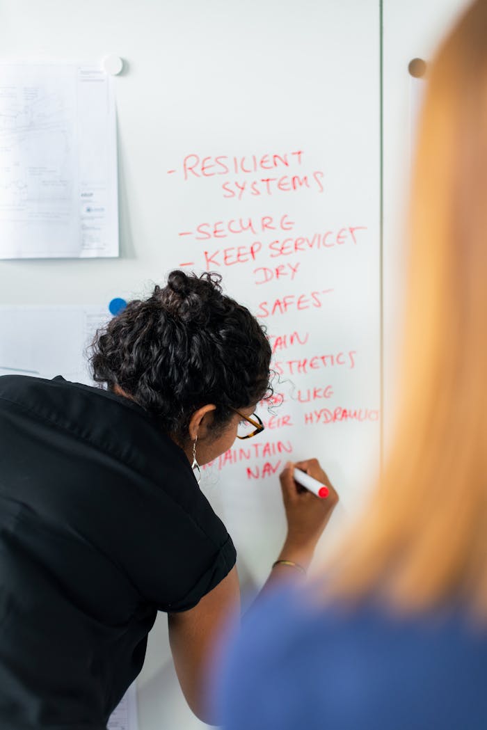 Female engineer writing strategy on a whiteboard during a business meeting.