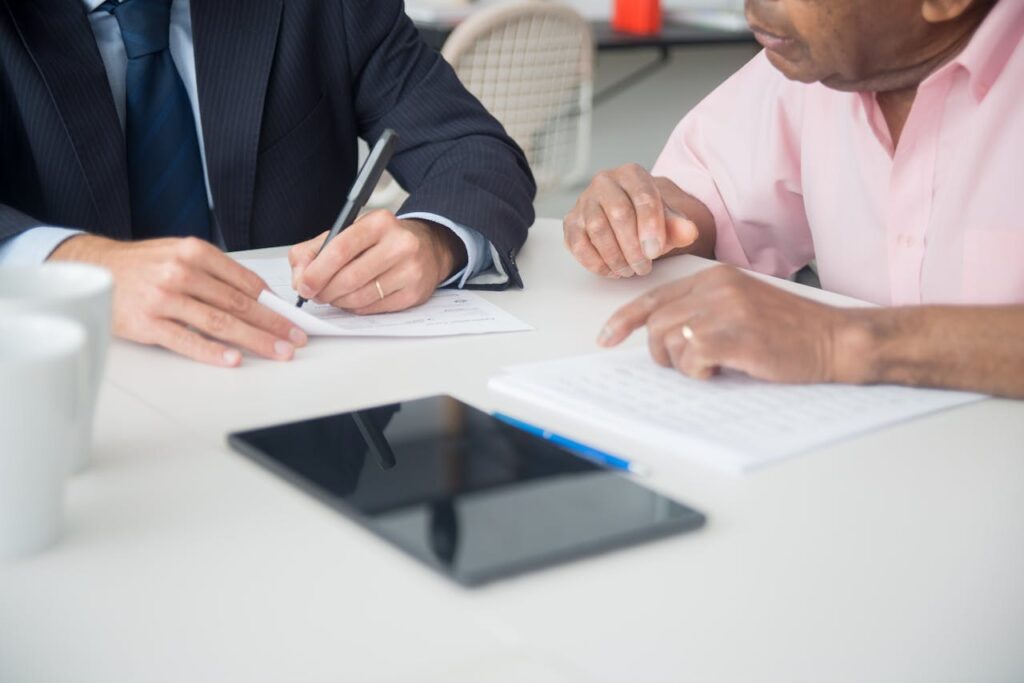 Two professionals discussing and signing documents in a business meeting.